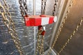 Metallic chain handle with red hook in technical room. Crane cargo hook