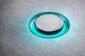 Metallic circular button illuminated by a soft turquoise glowing ring embedded in a brushed steel surface with modern sleek design Royalty Free Stock Photo