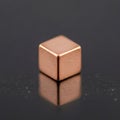 Metallic copper cube with smooth edges rests on a reflective black Royalty Free Stock Photo