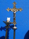 Metallic cross for catholic celebration with blue background and a chandelier with half burned candle