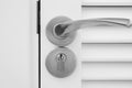 Metallic doorknob and keyhole on a white wooden door