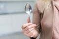 Metallic empty eating spoon in a human right hand with clipping path on white