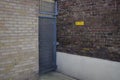 Metallic exit gate in between two walls next to a yellow danger sign