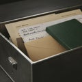 Metallic filing drawer containing various documents and a green notebook. Papers are Royalty Free Stock Photo