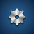 A metallic gear with an 8-tooth design is centered against a dark blue background. Royalty Free Stock Photo