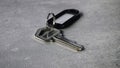 Metallic Key with Black Plastic Key Tag on Gray Surface Royalty Free Stock Photo