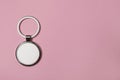 Metallic keychain with silver key ring on pale pink background, top view. Space for text