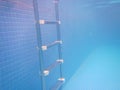 A metallic ladder at the bottom of a swimming pool filled with blue water. Royalty Free Stock Photo
