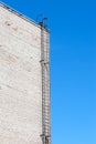 Metallic Ladder On White Brick Wall. Sky Background Royalty Free Stock Photo