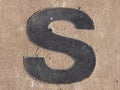 Metallic letter S embedded in pavement