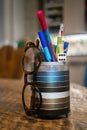 Metallic pencil holder with pencils, pens, dice and eyeglasses on the wooden table Royalty Free Stock Photo