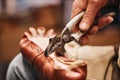 Metallic pliers in hand of male shoemaker fixing upper part of boot to sole