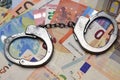 Metallic police handcuffs on euro banknotes suggesting corruption or criminal delinquency