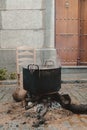 Metallic pot with boiling water on the fire surrounded by buildings