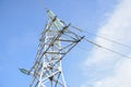 Metallic pylon of high-voltage power lines against blue sky with clouds. Bottom view. Copy space Royalty Free Stock Photo