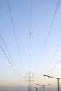 Metallic pylon of high-voltage power lines and street lighting poles against the evening twilight sky Royalty Free Stock Photo