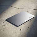 A metallic, rectangular card with a brushed texture lies on a rough, concrete surface. Royalty Free Stock Photo