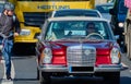 Metallic red Mercedes Daimler Benz, classic old antique car, is driven by a driver wearing sunglasses