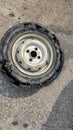 Metallic rim of an overinflated car tyre kept on the main road after it burst
