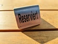 Metallic sign on a wooden table with the german word for reserved on it