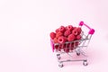 Metallic Small Shopping Cart with raspberries inside on Pink background. Shopping, purchases, supermarket, sale, mall concept