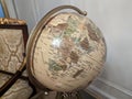 a globe is sitting on a metal stand in front of a chair