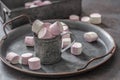 Metallic vintage tray, surface and cup with pink and white marshmallows inside the cup and scattered around the tray as