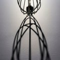 A metallic wire whisk casting an intricate shadow on a textured white surface Royalty Free Stock Photo