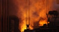 Metallurgical heavy industry background. Large dark workshop of foundry factory in puffs of orange smoke from blast