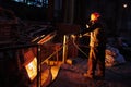 Metallurgist steelmaker takes a sample of liquid metal from a ladle.