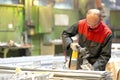 Factory worker using angle grinder during manufacture process