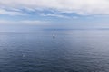 Metaphor for solitude, loneliness and purity: white yacht with white sail, silver gull in flight over Bay of Biscay