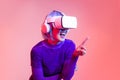 Metaverse concept happy woman in purple shirt wearing vr goggles headset finger pointing touching playing on the peach screen Royalty Free Stock Photo