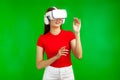 Metaverse Photo Concepts, Young pretty asian woman in red t-shirt wearing vr headset isolated on green background Royalty Free Stock Photo