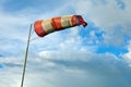 Meteorology wind bag for marine navigation. Red and white windsock blows against a blue sky Royalty Free Stock Photo