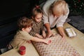 Methodical grandmother teaches granddaughter how to wrap a present.