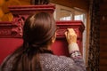 Meticulous process of furniture patination. Woman with brush aging red colored wooden cupboard with brilliant carved