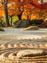 Meticulously raked sand patterns create a serene landscape in a Japanese Zen garden, complemented by vibrant autumn Royalty Free Stock Photo