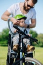 Metodical father strapping bike helmet on his infant son