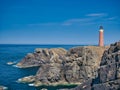 The 37 metre red brick tower of the Butt of Lewis Lighthouse over high sea cliffs at the most northerly point of the Isle of Lewis