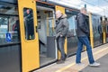 Metro light rail train on a platform in station with people boarding and exiting open doors