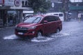 A red Toyota Innova wades through flash floods caused by heavy rains. Monsoon season or thunderclouds.