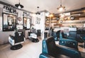 Interior of a typical modern barbershop with four chairs. No people in shot