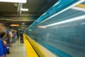 A metro train transit runs by as the people wait. The Montreal Metro, Quebec, Canada