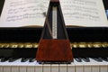 Metronome in motion on a piano with a music sheet in background