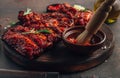 Mexican barbecued ribs seasoned with a spicy tomato sauce served on a wooden chopping board on a dark background Royalty Free Stock Photo