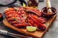 Mexican barbecued ribs seasoned with a spicy tomato sauce served on a wooden chopping board on a dark background Royalty Free Stock Photo