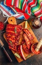 Mexican barbecued ribs seasoned with a spicy tomato sauce served on a wooden chopping board on a dark background Royalty Free Stock Photo