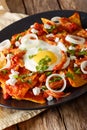 Mexican breakfast: chilaquiles with egg and chicken close-up. Vertical