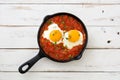 Mexican breakfast: Huevos rancheros in iron frying pan on white wooden table top view Royalty Free Stock Photo